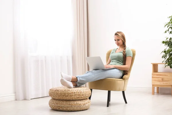 Junge Frau mit Laptop sitzt zu Hause im Sessel — Stockfoto