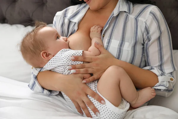 Mujer amamantando a su pequeño bebé en la cama en interiores — Foto de Stock