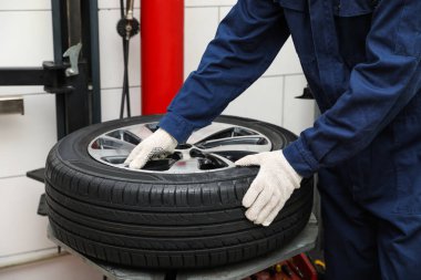 Araba servisinde lastik montaj makinesiyle çalışan adam, yakın plan.