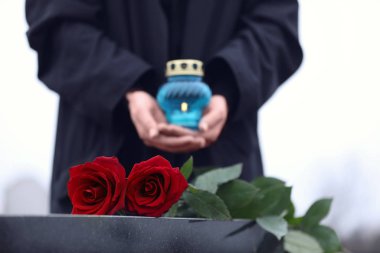 Dışarıda mumu olan kadın, kırmızı güllere odaklan. Cenaze töreni.