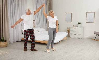 Mutlu olgun çift yatak odasında dans ediyor.