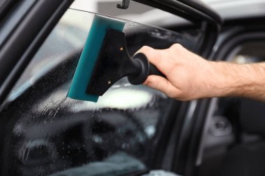 Atölyede renkli araba camlarını yıkayan işçi, yakın plan.