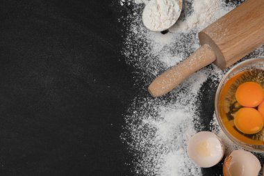 Düz kompozisyon, yumurta ve diğer malzemeler siyah masa üzerinde, metin için boşluk. Pasta yapmak.