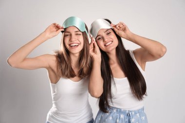 Açık gri arka planda uyku maskesi takan güzel kadınlar..