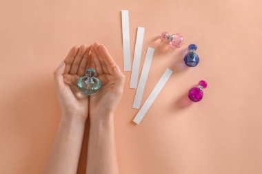 Şeftali arka planında parfüm şişesi olan bir kadın.