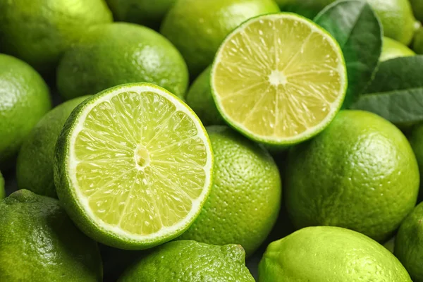 Świeże dojrzałe soczyste limonki jako tło, zbliżenie — Zdjęcie stockowe