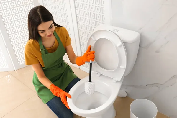 Jonge vrouw schoonmaken toilet kom in badkamer — Stockfoto