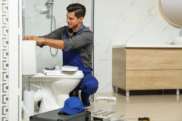 Fontanero profesional trabajando con inodoro en el baño — Foto de Stock