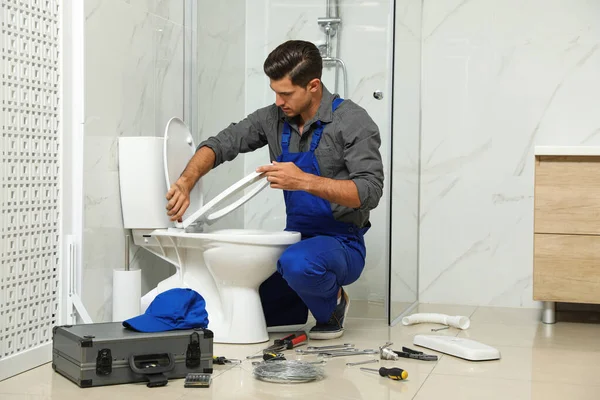 Професійний сантехнік, що працює з унітазом у ванній кімнаті — стокове фото