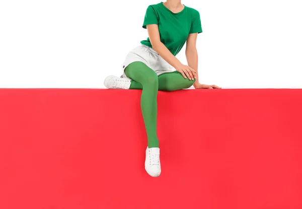 Kvinne med grønne strømpebukser sittende på farget bakgrunn, tett inntil – stockfoto