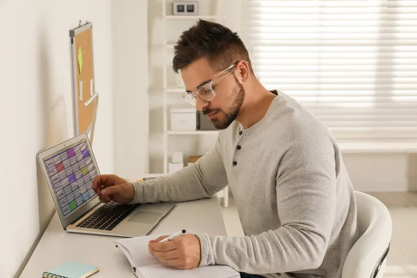 Genç adam ofisteki dizüstü bilgisayarında takvim uygulaması kullanıyor. — Stok fotoğraf