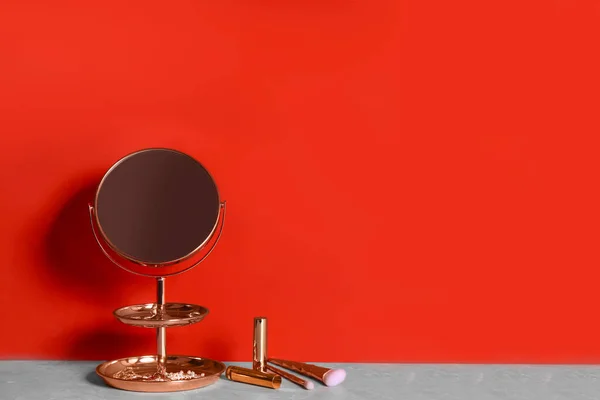 赤い壁の近くの灰色の大理石のテーブルの上の小さな鏡と化粧品 テキストのスペース — ストック写真