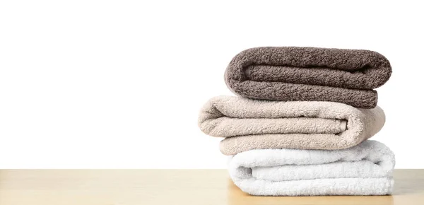 Folded fresh clean towels for bathroom on table against white ba — 스톡 사진