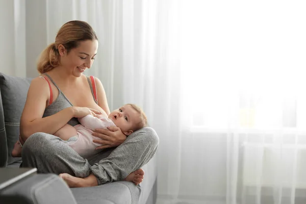 Jovem mulher amamentando seu bebê em casa. Espaço para texto — Fotografia de Stock