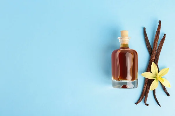 Flat lay composition with vanilla extract on light blue background. Space for text