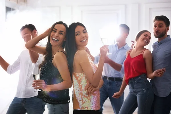 Couple of happy friends with champagne dancing at party — Stock Photo, Image
