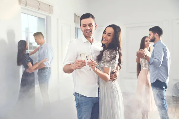 Adorável jovem casal com copos de champanhe na festa de dança — Fotografia de Stock