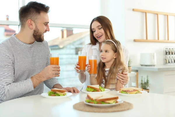 幸せな家族はキッチンのテーブルでサンドイッチと朝食を持っています — ストック写真