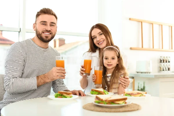 Щаслива сім'я снідає з бутербродами за столом в кущах — стокове фото