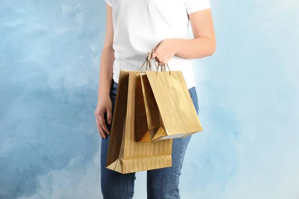 薄い青の背景に金の買い物袋を持つ女性 クローズアップ — ストック写真