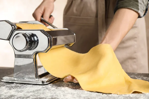 Mujer preparando masa con máquina de hacer pasta en la mesa, primer plano — Foto de Stock