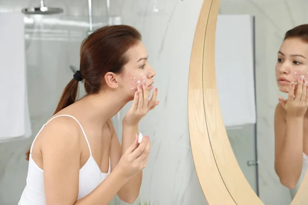 Menina adolescente com problema de acne aplicando creme perto do espelho na bathro — Fotografia de Stock