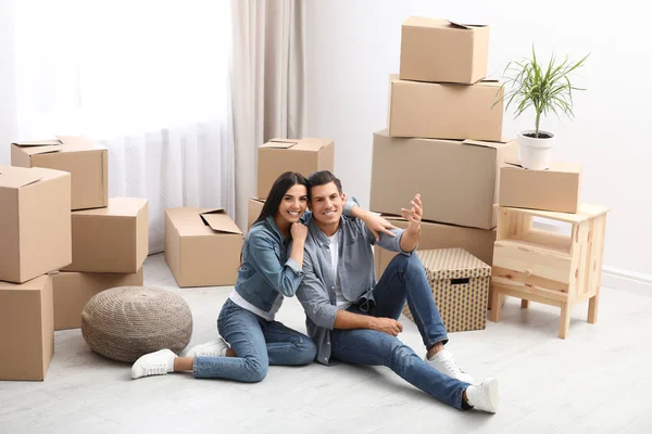 Pareja feliz en la habitación con cajas de cartón en el día en movimiento —  Fotos de Stock