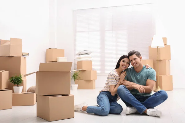 Happy couple in room with cardboard boxes on moving day — Stock Photo, Image