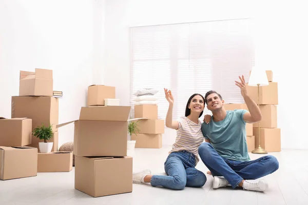 Pareja feliz en la habitación con cajas de cartón en el día en movimiento —  Fotos de Stock