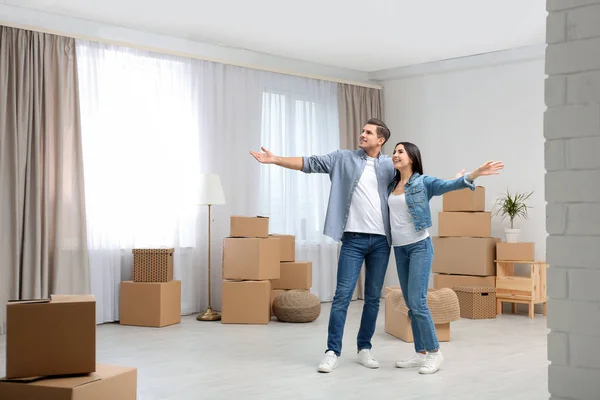 Pareja feliz en la habitación con cajas de cartón en el día en movimiento —  Fotos de Stock