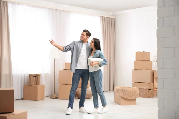 Pareja feliz en la habitación con cajas de cartón en el día en movimiento —  Fotos de Stock