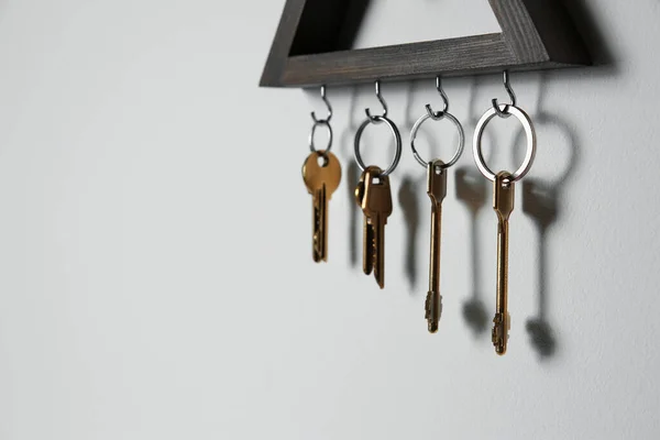 Wooden key holder on light grey wall. Space for text — Stock Photo, Image