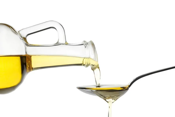 Pouring cooking oil from jug into spoon on white background — Stock Photo, Image