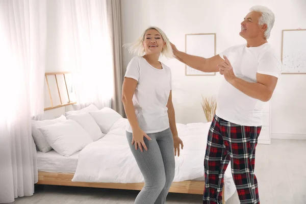 Happy mature couple dancing together in bedroom