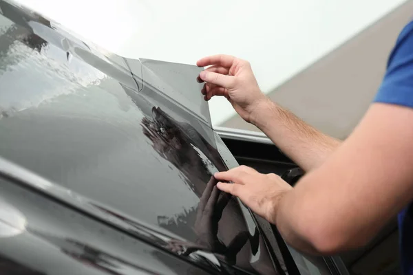 Obrero teñido ventana del coche con papel de aluminio en el taller, primer plano — Foto de Stock