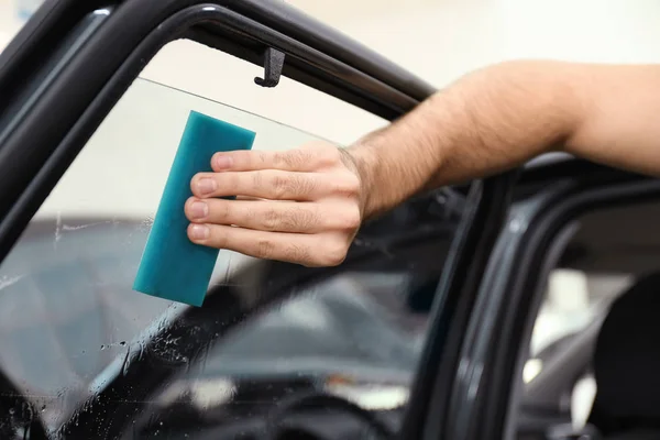 Worker washing tinted car window in workshop, closeup — Stock Photo, Image