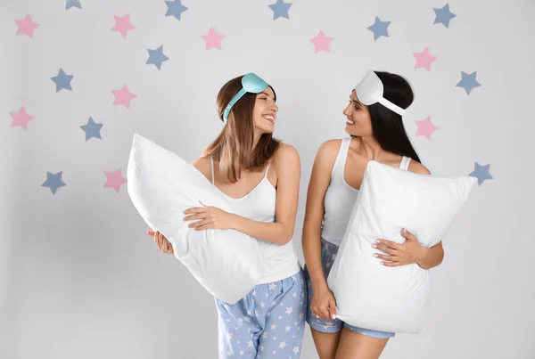 Hermosas mujeres con almohadas sobre fondo gris claro. Hora de dormir — Foto de Stock