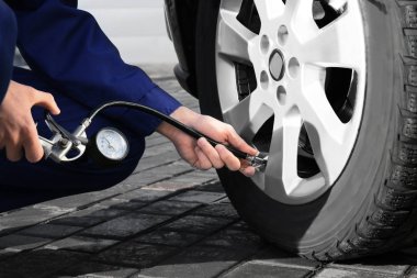 Tamirci araba servisinde lastik basıncını kontrol ediyor.