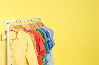 Parlak giysiler sarı arka planda asılı duruyor, mesaj için yer var. Gökkuşağı renkleri