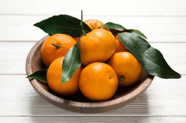 Taze mandalinalar ve beyaz ahşap masadaki yapraklar. Citrus meyvesi.
