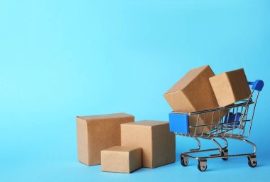 Açık mavi arka planda alışveriş arabası ve kutular, mesaj için yer. Lojistik ve toptan satış kavramı