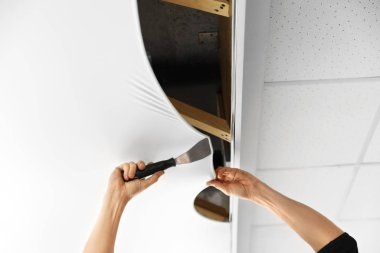 Tamirci odaya beyaz esnek tavan kuruyor.