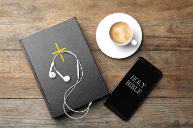 İncil, telefon, bir fincan kahve ve ahşap arka planda kulaklık. Dini sesli kitap