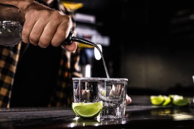 Barda bardaklara Meksika tekilası dolduran barmen.