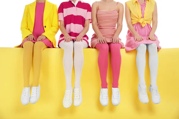 Women wearing bright tights sitting on color background, closeup — Stock Photo, Image