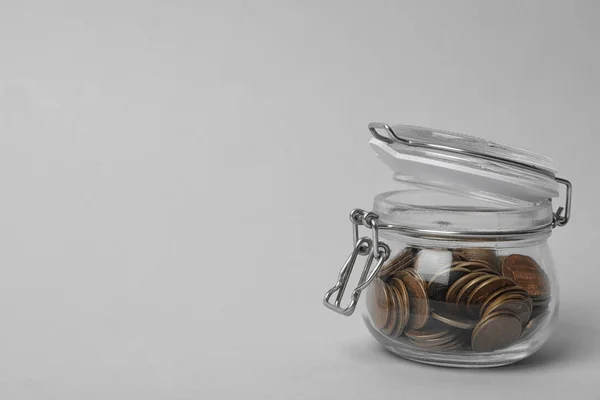 Glass jar with coins on light background, space for text — 스톡 사진