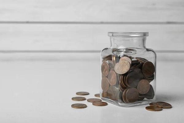 Glass jar with coins on white table, space for text — 스톡 사진