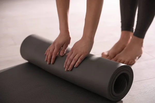 Женщина катит коврик для йоги в студии, крупный план — стоковое фото