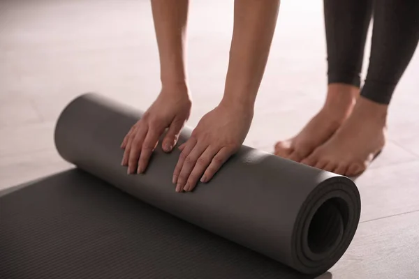 Woman rolling yoga mat in studio, closeup — Stock Photo, Image