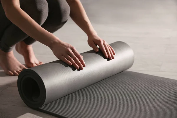 Woman rolling yoga mat in studio, closeup — Stock Photo, Image